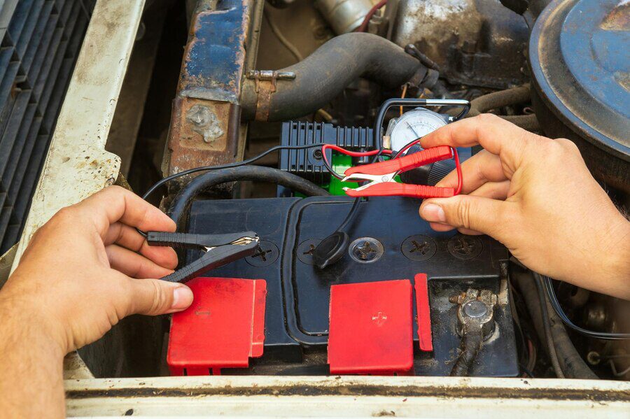 close-up-driver-hands-charging-old-car-battery-using-electricity-through-jumper-cables_192985-2080